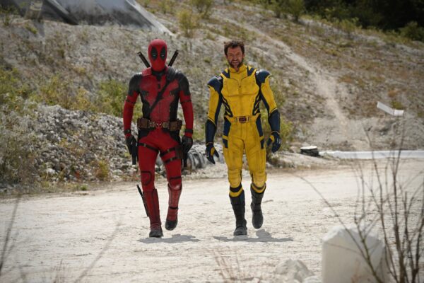 Deadpool e Wolverine caminhando em uma estrada de terra. Os personagens estão com uniformes mais próximos de suas versões nos quadrinhos.